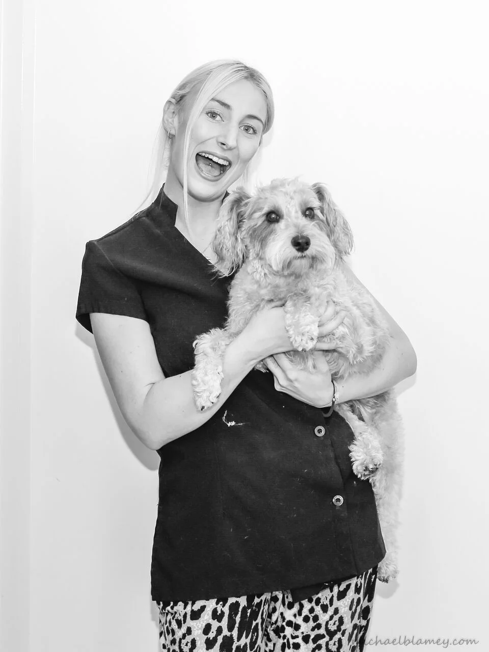Groomer Hannah laughing, holding an apricot schnoodle